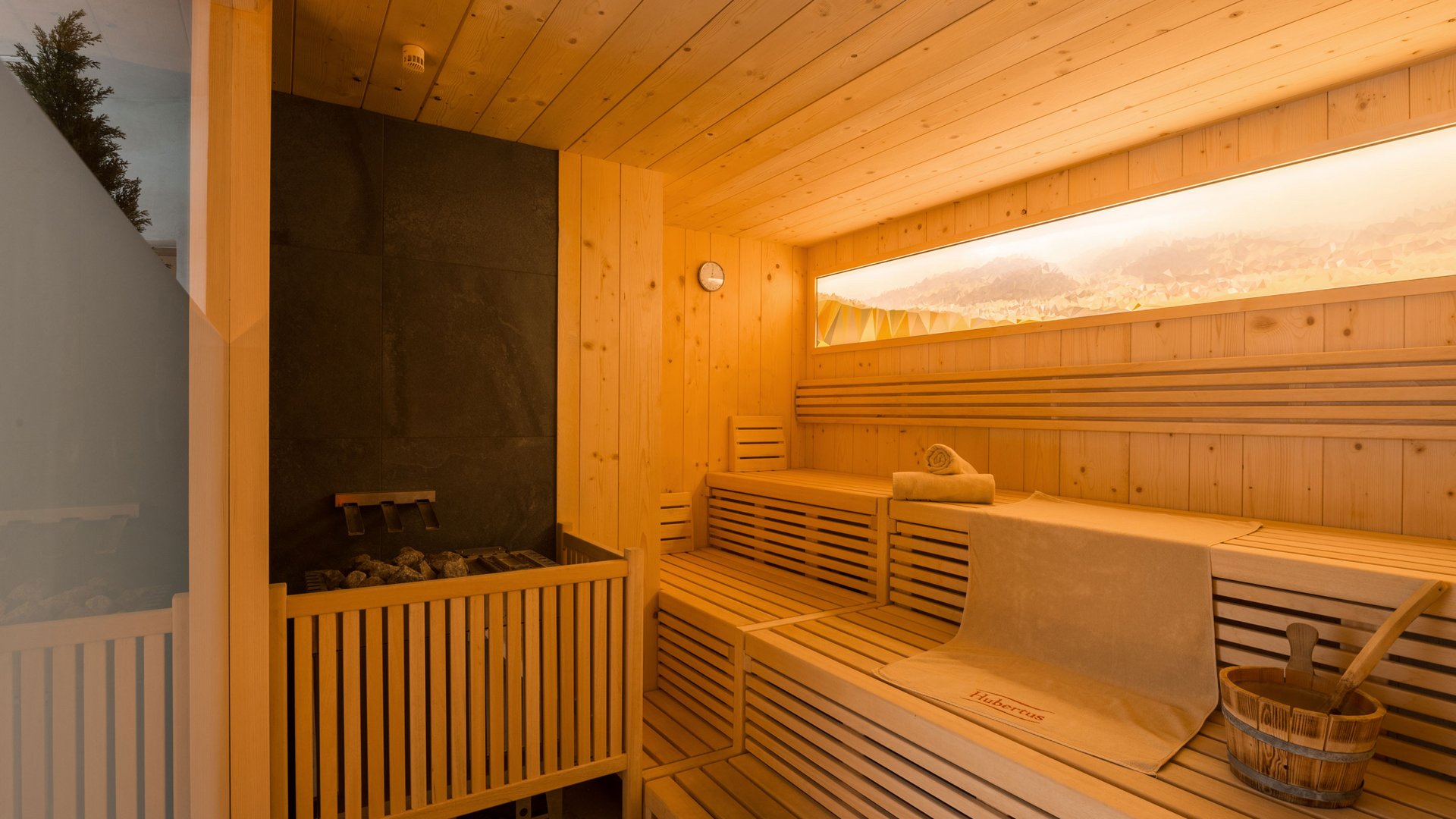 Our sauna, Plan de Corones/Kronplatz in full view Modern wooden sauna interior with benches, bucket, and towels