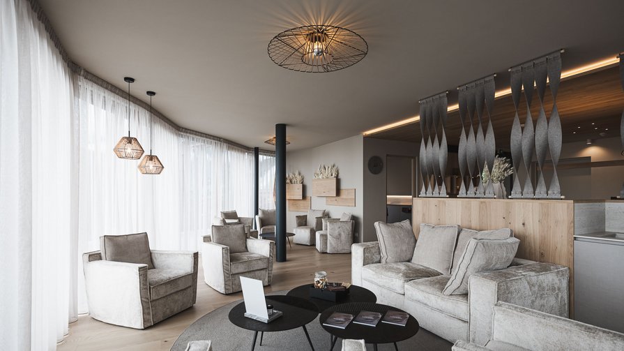 Discover our expanded wellness area on 400 sqm Modern living room with light armchairs, sofa, and decorative hanging lamps