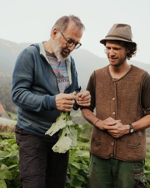 Atelier Moessmer Norbert Niederkofler Due uomini esaminano una pianta di verdura in un campo agricolo