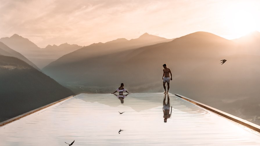 Explore the many facets of life in our hotel and its surroundings People at infinity pool with mountain view at sunset