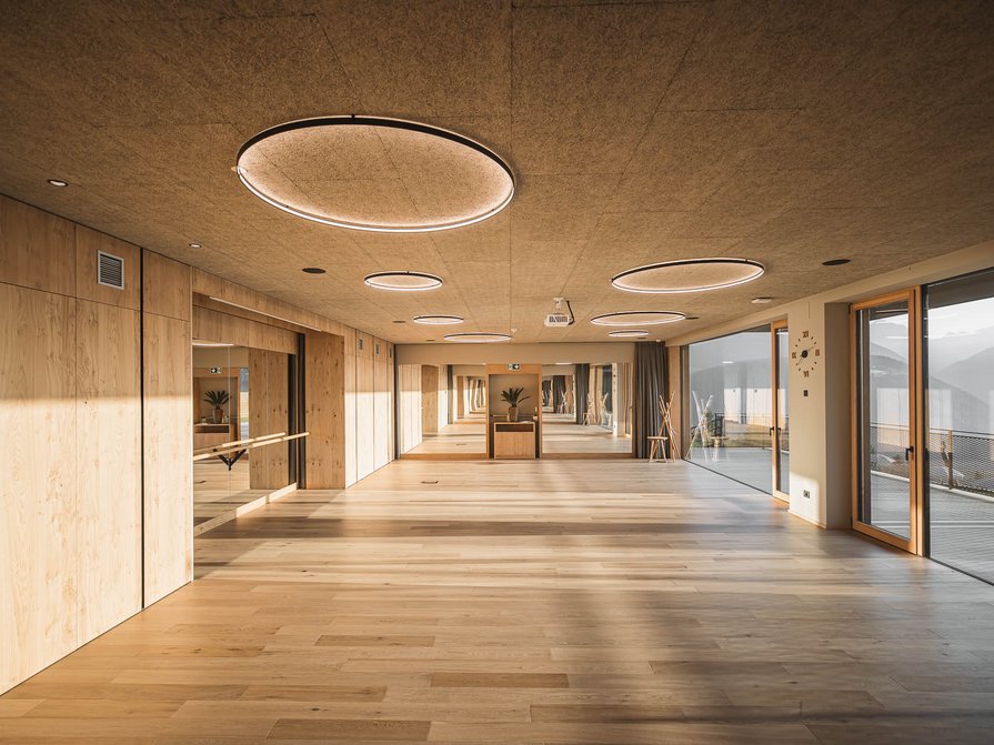 Our 5-star hotel in Italy between heaven and earth Large room with wooden floor, mirrored wall and large windows with mountain view