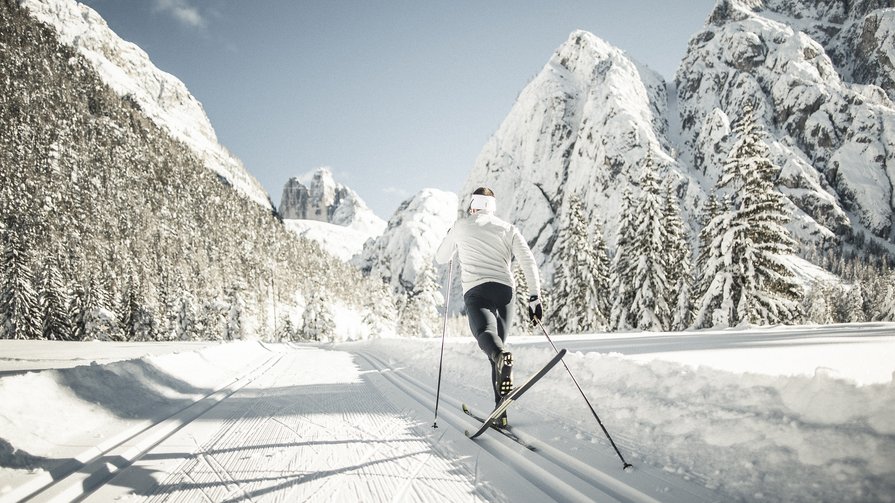 Winter holidays at Plan de Corones/Kronplatz: incredibly diverse Cross-country skier on snowy trail with snowy mountains and trees in background