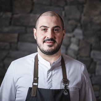 Experience moments of culinary magic Portrait of a male chef wearing white jacket and apron in front of stone wall
