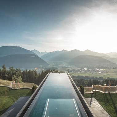 Awards & Press Infinity-Pool mit Bergblick bei Sonnenuntergang in einem Luxushotel