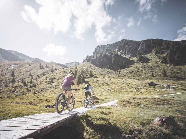 Biken am Kronplatz: einzigartig Zwei Mountainbiker fahren auf einem Pfad in den Bergen bei sonnigem Wetter
