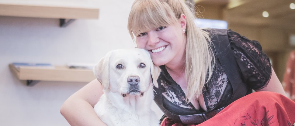 Current news and stories from Olang A woman in traditional dress hugging a white Labrador on a carpet