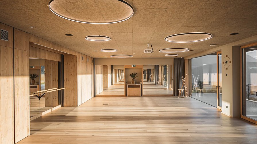 Vielfältige Indoor-Aktivitäten für Körper und Geist Großer heller Raum mit Holzboden, Spiegelwand und runden Deckenleuchten