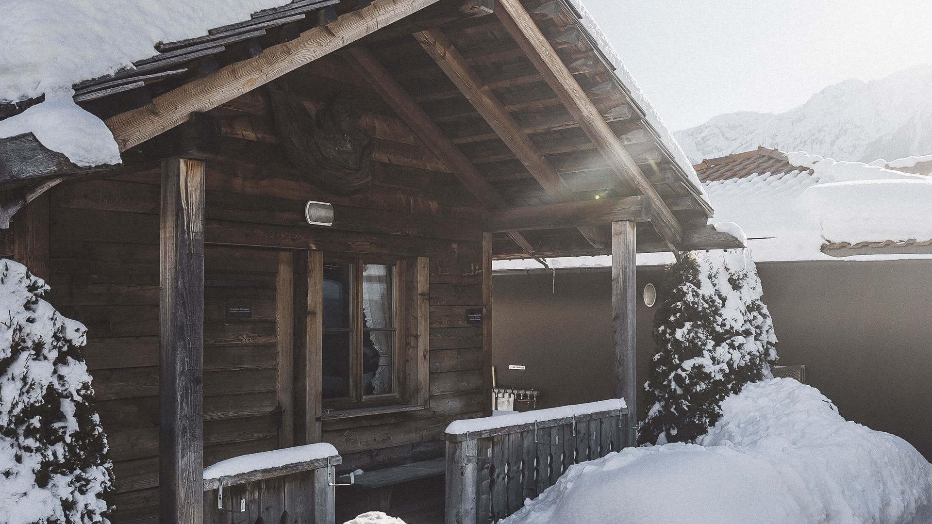 Our sauna, Plan de Corones/Kronplatz in full view Snow-covered wooden cabin with porch on a sunny winter day