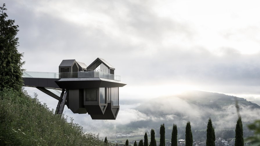 Innovation und Natur im Alpin Panorama Hotel Hubertus Moderne Aussichtplattform auf Stelzen über Blick auf nebliges Tal und Berge