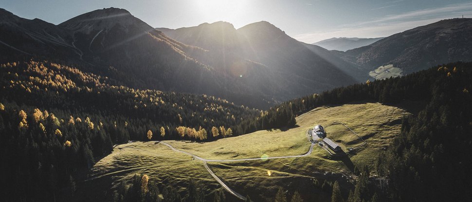 Unser Hotel in Olang zwischen Himmel und Erde Sonnenlicht über einer grünen Alm in den Bergen mit einem kleinen Haus