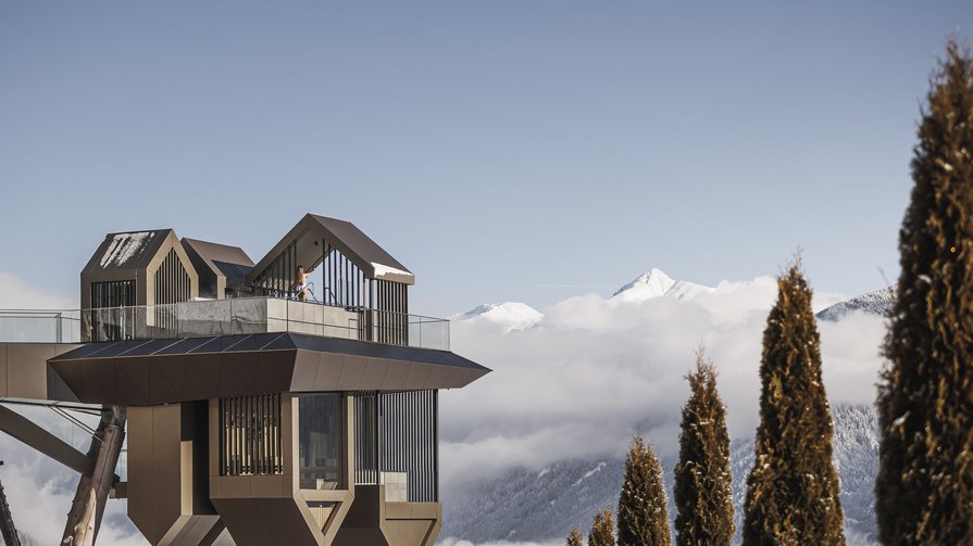 Highlights at the Hubertus Modern mountain station above trees with snow-covered peaks in background