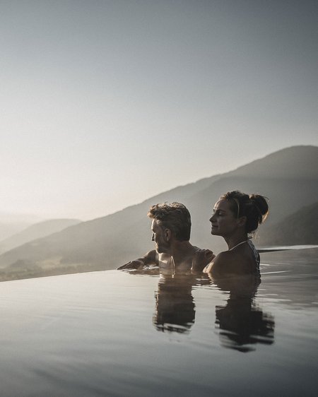 Our current catalogue for downloading Couple relaxing in infinity pool overlooking mountains at sunset