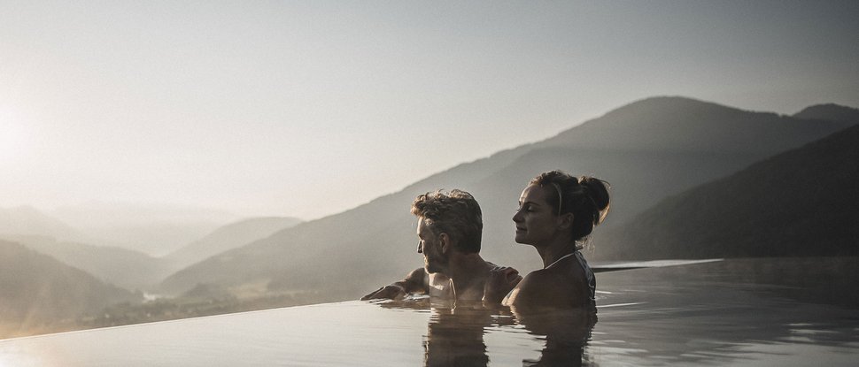 Our current catalogue for downloading Couple relaxing in infinity pool overlooking mountains at sunset