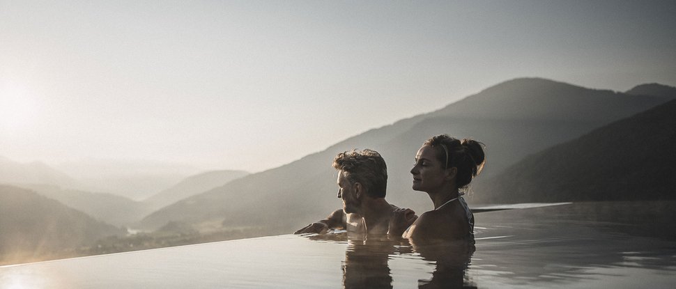 Ultime novità e storie da Valdaora Coppia rilassata in piscina a sfioro con vista sulle montagne al tramonto