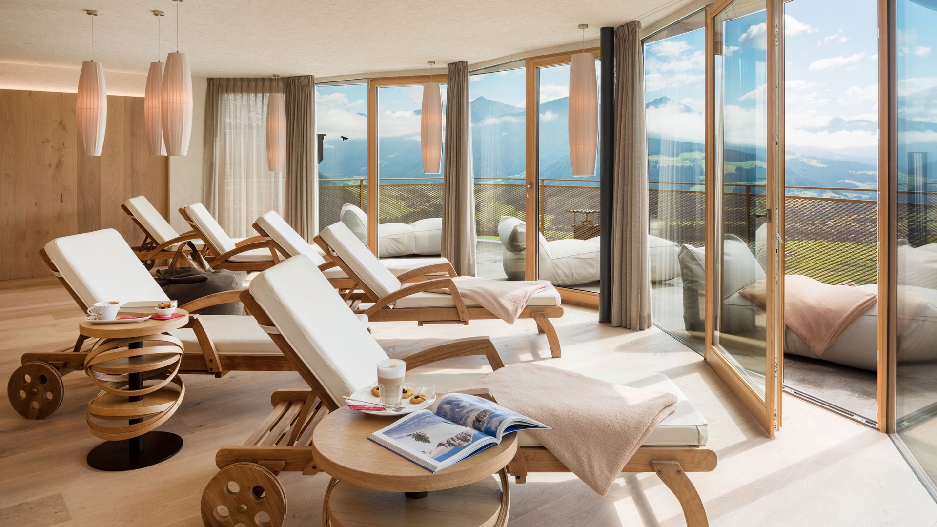 Unsere Sauna, den Kronplatz im Blickfeld Entspannungsraum mit Liegestühlen und Bergblick durch große Fenster