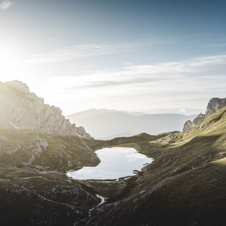 Shopping a Brunico e molto altro ancora Alba sopra un lago di montagna in un paesaggio verde collinare