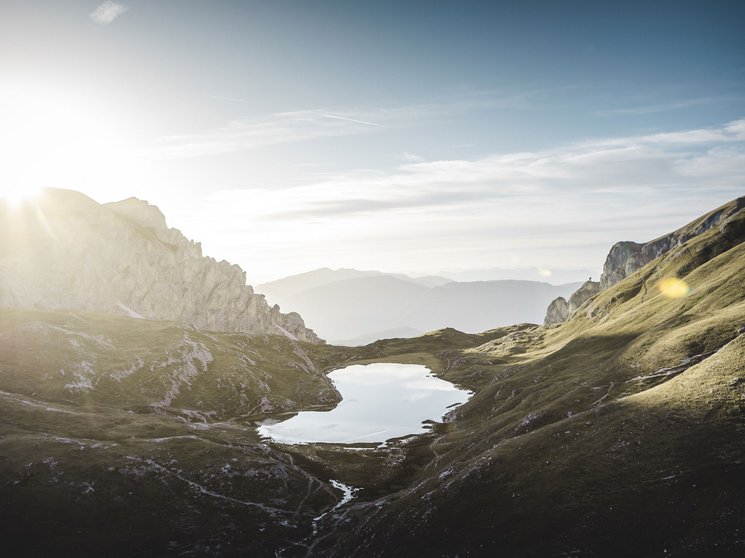 Bruneck: Shopping und mehr Sonnenaufgang über einem Bergsee in einer grünen Gebirgslandschaft