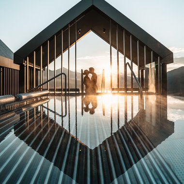 Awards & Press Couple embraces in an outdoor heated pool at sunset