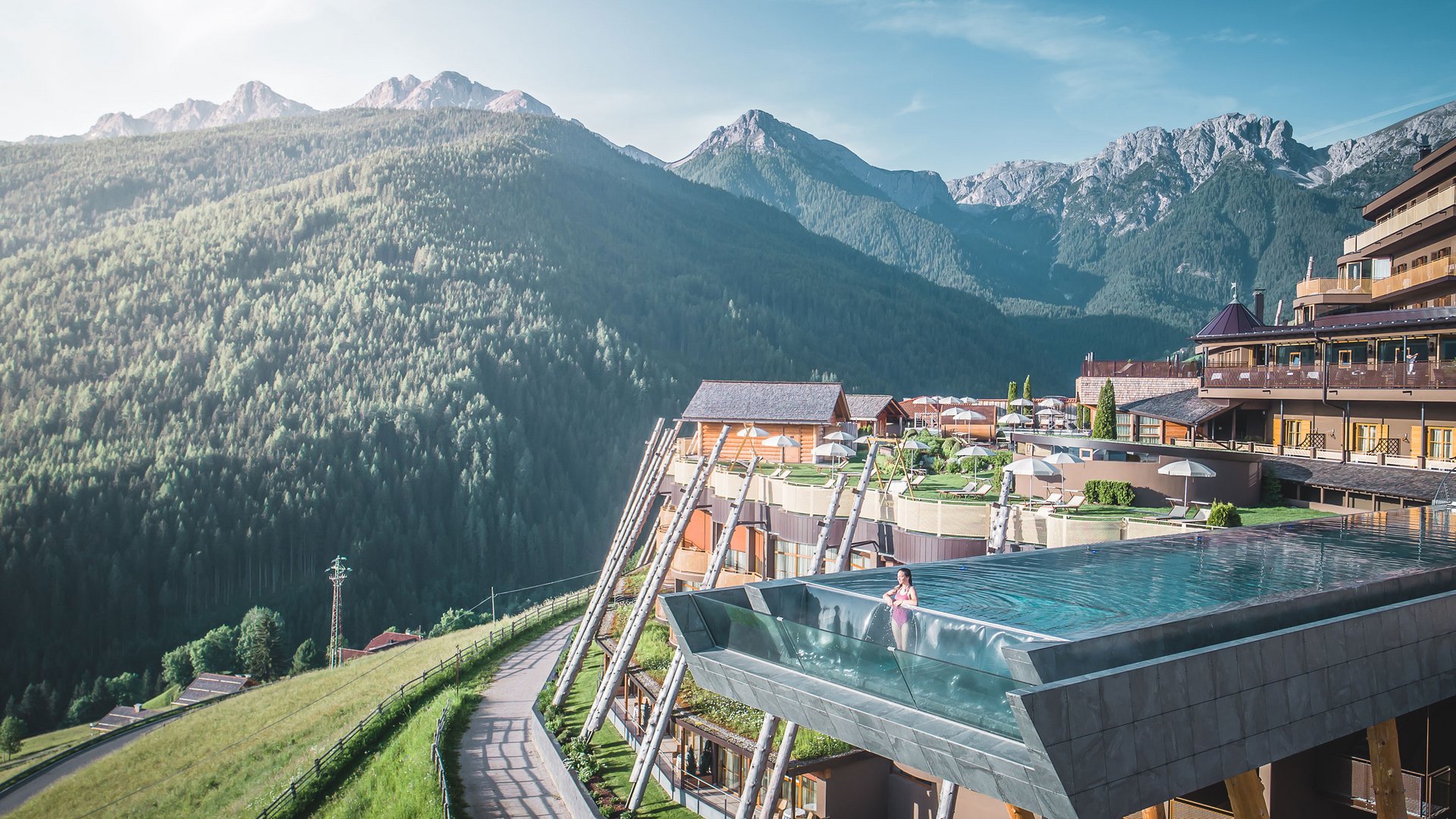 Current news and stories from Olang Infinity pool at mountain resort overlooking forested alpine peaks