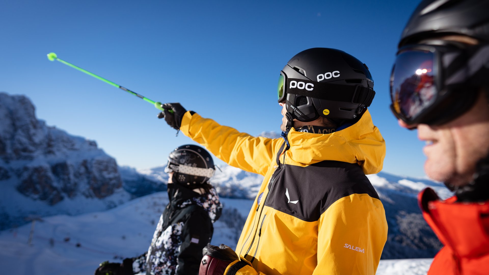 The best hotel at Plan de Corones/Kronplatz Skiers in colorful gear with helmets pointing at snowy mountains