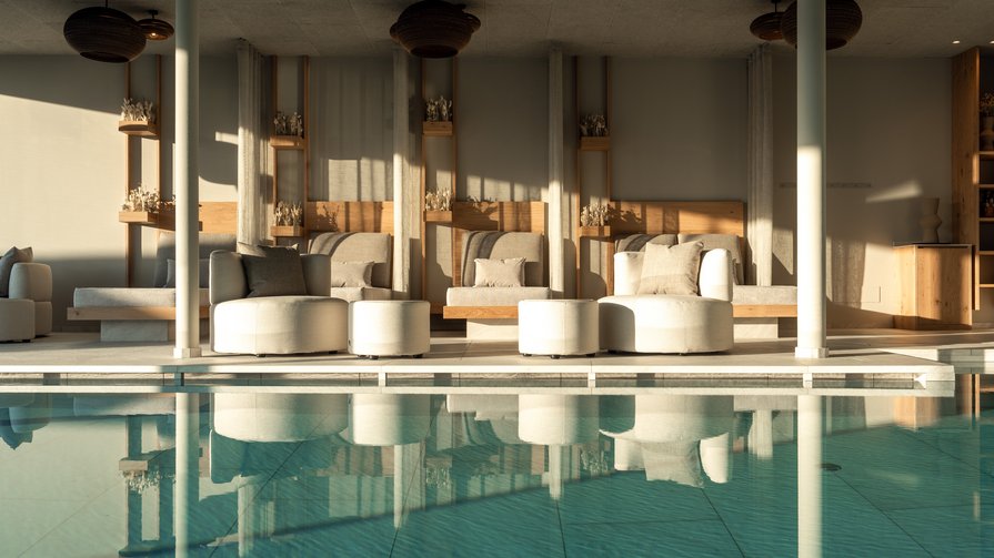 Neues Wohlgefühl im Hubertus Gemütliche Sitzplätze neben einem stillen Innenpool mit Sonnenlicht