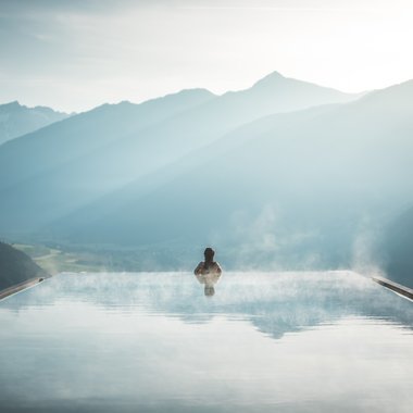 Vacanza a Plan de Corones: un’avventura Persona in piscina infinity con vapore che guarda montagne nebbiose