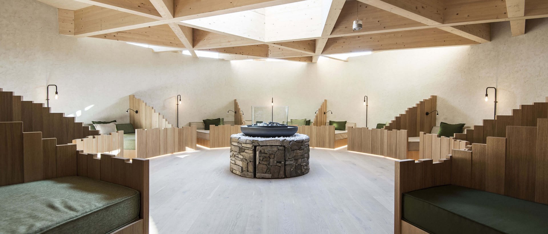 Erholung auf allen Ebenen des Seins Moderner Ruheraum mit Holzdecke und Sitzbereichen um einen zentralen Steinkamin