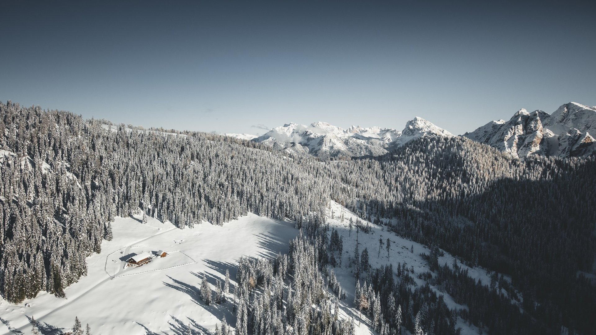 Winterwandern in der Kronplatz-Region Schneebedeckte Berghütte umgeben von verschneiten Tannen und Bergen