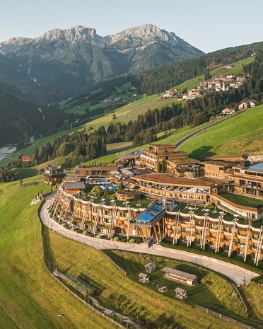 Aktuelle News und Geschichten aus Olang Luxushotel auf grüner Bergwiese vor den Alpen bei klarem Himmel
