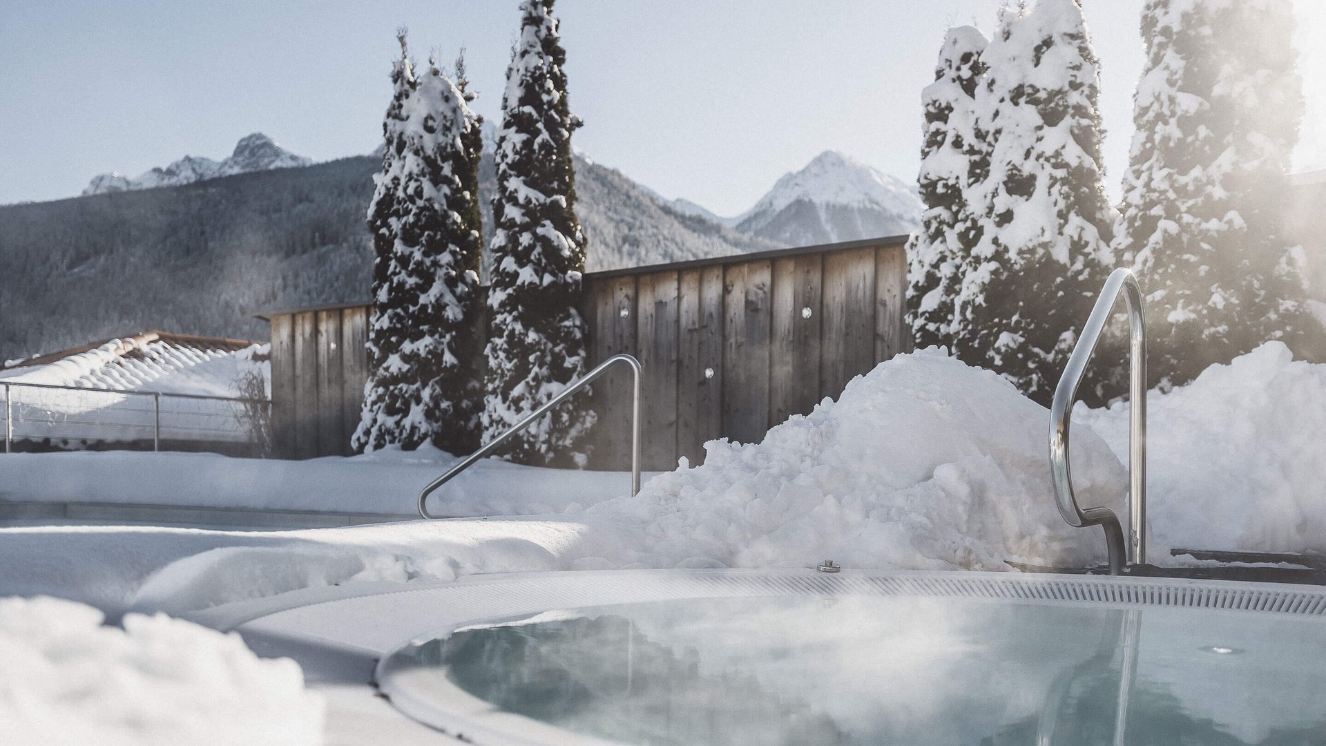 Our Sky Pool in South Tyrol, a rare beauty Outdoor hot tub with snow-covered trees and mountains in the background.