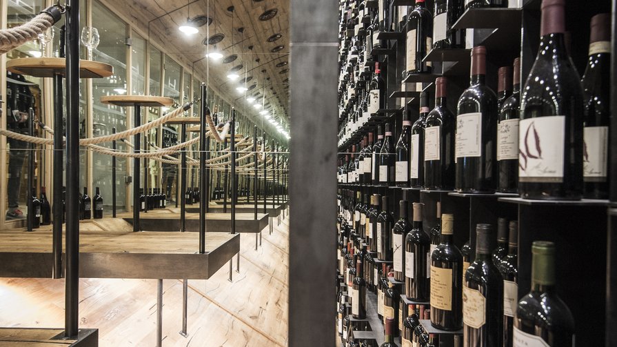 Unser Weinangebot entdecken Weinkeller mit vielen Weinflaschen und Holzverkleidung