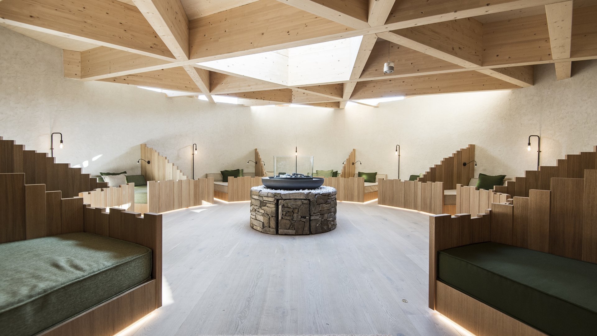 Our sauna, Plan de Corones/Kronplatz in full view Modern room with wooden seating areas and central stone table under wooden grid ceiling