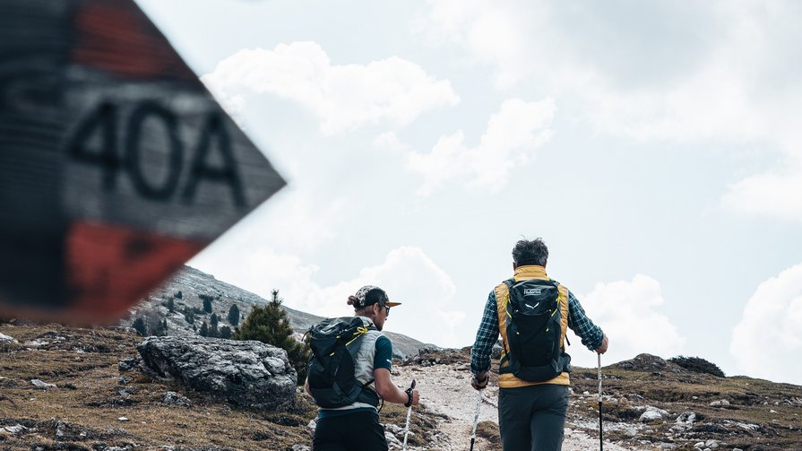 Ein Juwel in den Pragser Dolomiten Zwei Wanderer mit Rucksäcken gehen auf einem felsigen Bergpfad