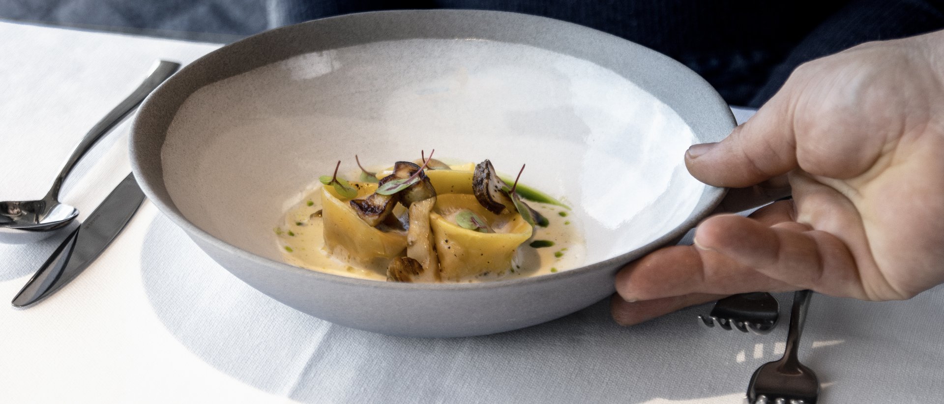 Hotel gourmet in Alto Adige per buongustai Donna riceve piatto con pasta raffinata e funghi al ristorante