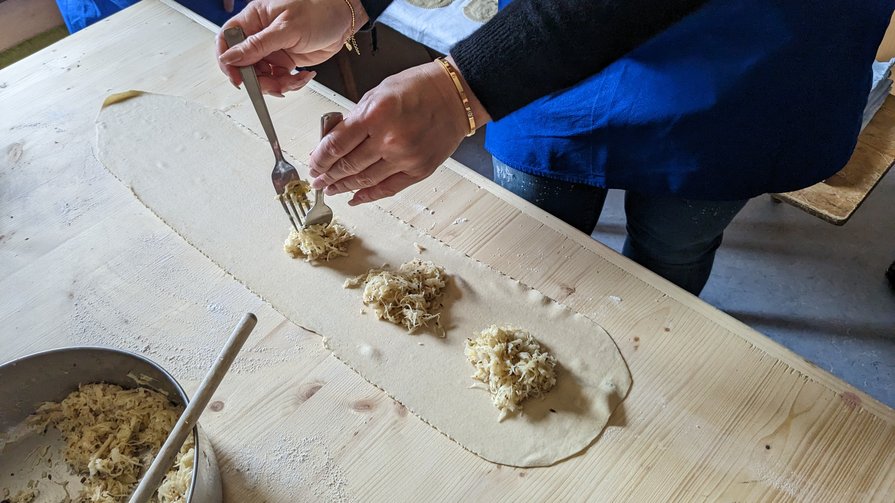 Traditionelle Südtiroler Küche Person verteilt Füllung auf Teig in einer Küche