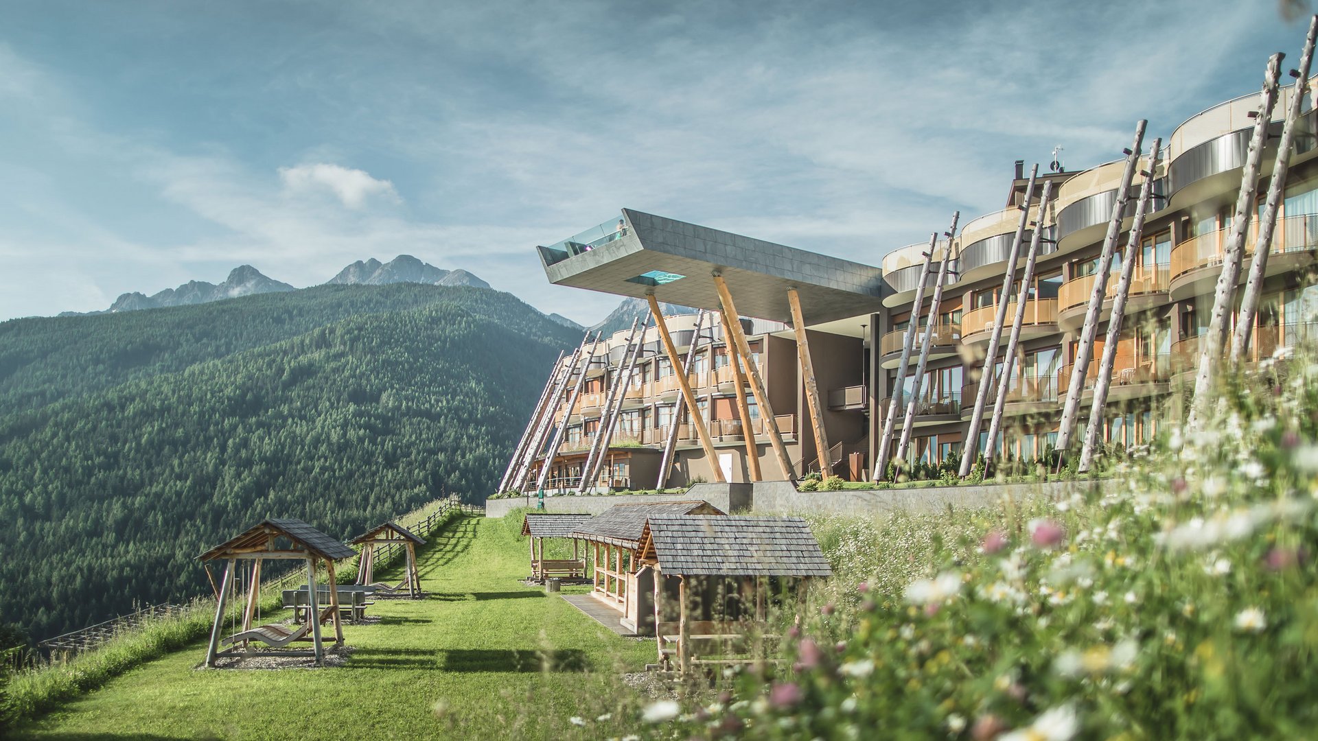 Il nostro buono vacanza: l’Alto Adige in formato regalo Hotel moderno con piattaforma panoramica in montagna e prato fiorito