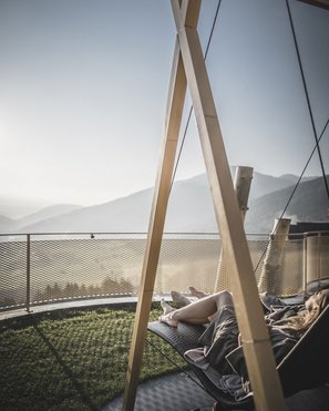 Our wellness hotel in Val Pusteria for relaxation seekers Person relaxing on a hammock with mountain view