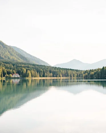 Aktuelle News und Geschichten aus Olang Bergsee mit reflektierenden Bäumen und einem Haus am Ufer