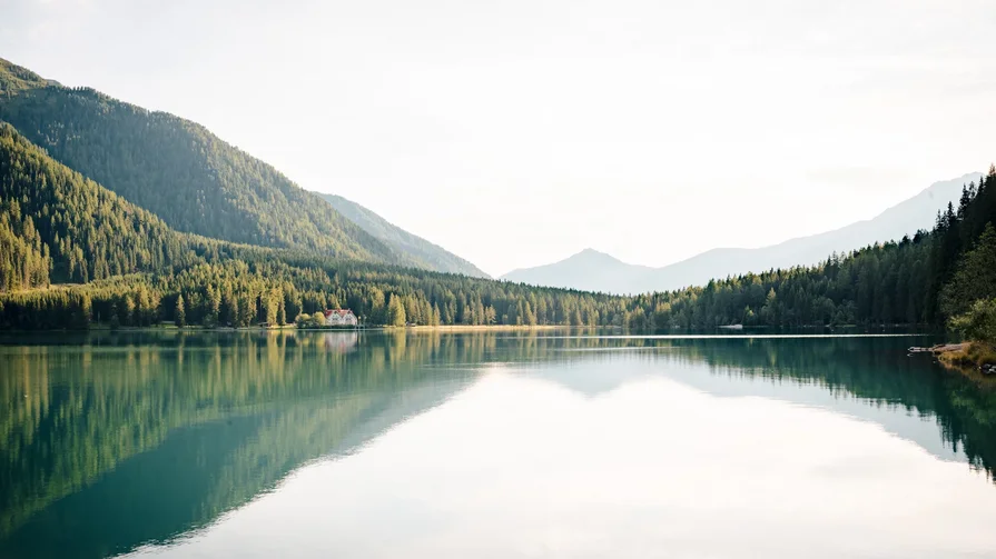 Ganz ohne Eile Bergsee mit reflektierenden Bäumen und einem Haus am Ufer